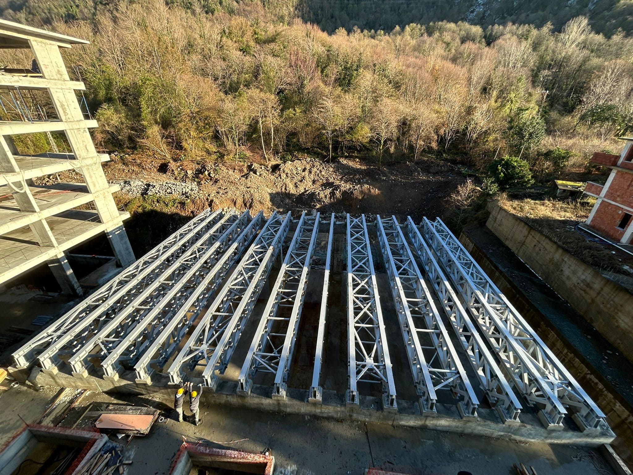 Çelik konstrüksiyon şantiyesinde montaj ekipleri ve vinç ile çelik taşıyıcı elemanların kurulumu